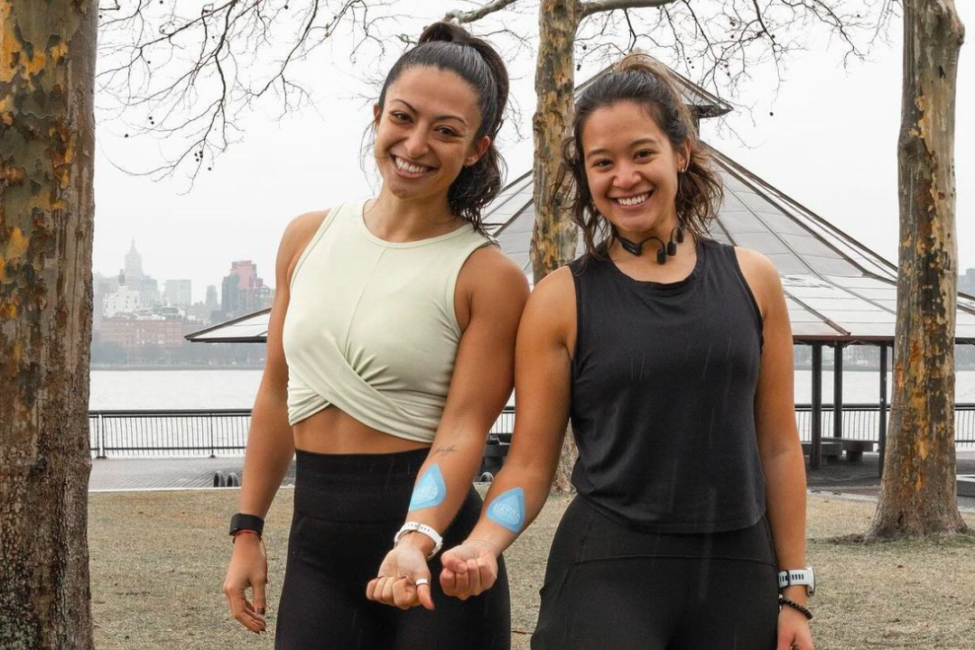 Two women in athletic wear standing outdoors with a scenic background
